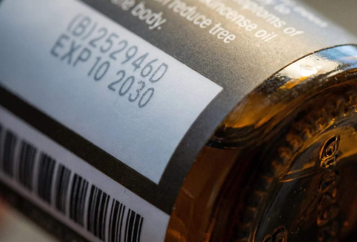 Macro close-up of a dōTERRA essential oil bottle showing its Source to You batch code and expiry date