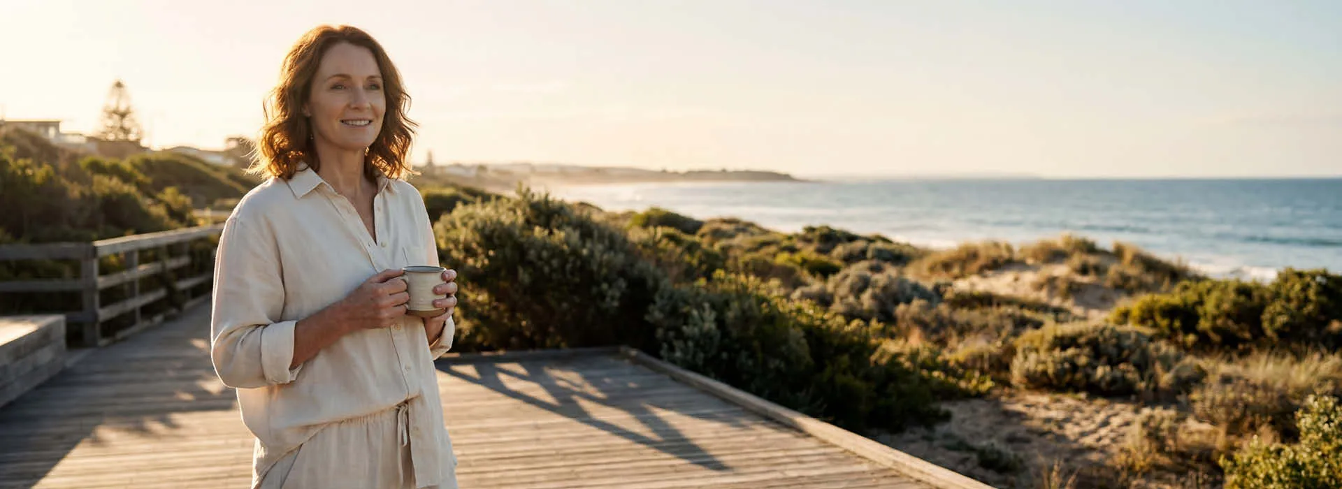 A woman enjoying a calm morning by the coast with a cup of tea